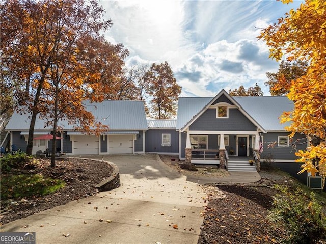 view of front facade with a porch, concrete driveway, metal roof, and an attached garage