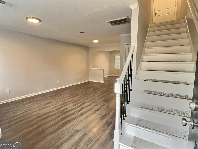 spare room with crown molding, dark hardwood / wood-style flooring, and a textured ceiling