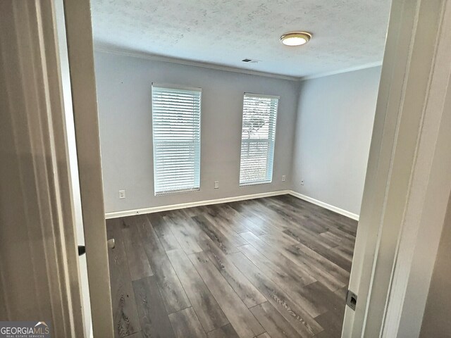 empty room featuring dark hardwood / wood-style flooring and ornamental molding