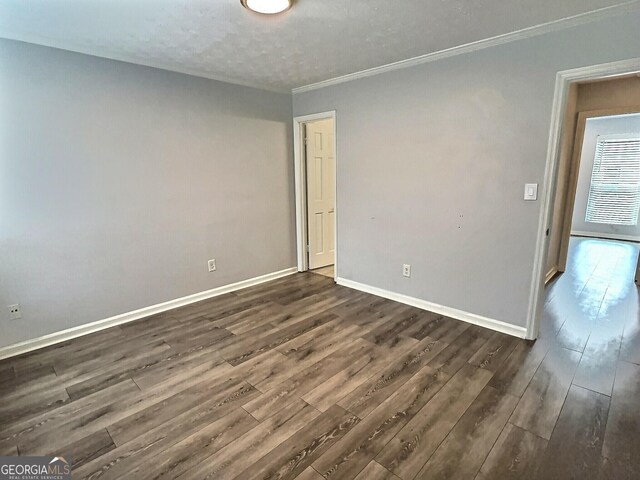 empty room featuring crown molding, dark wood-type flooring, and a textured ceiling