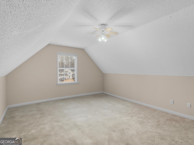 additional living space with lofted ceiling, light colored carpet, and a textured ceiling