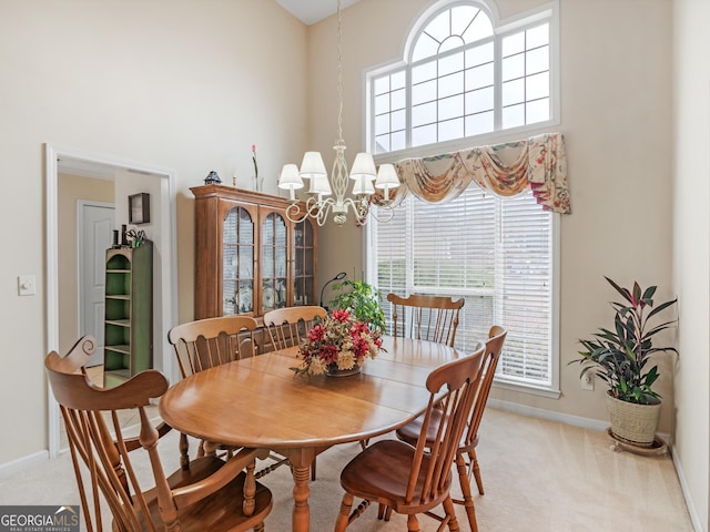 dining space featuring a high ceiling, light carpet, and an inviting chandelier