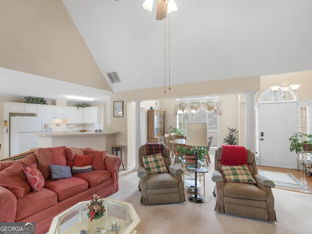 living room with ceiling fan with notable chandelier, high vaulted ceiling, and decorative columns