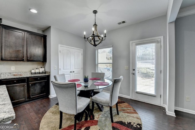 dining room featuring dark wood-type flooring, a healthy amount of sunlight, and a chandelier