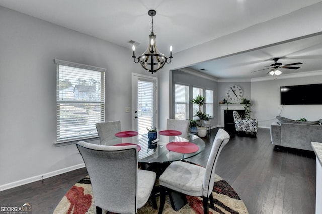 dining room with dark wood-type flooring, ornamental molding, and ceiling fan with notable chandelier