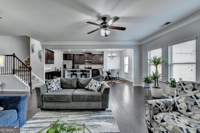 living room with ornamental molding, dark hardwood / wood-style floors, and ceiling fan with notable chandelier