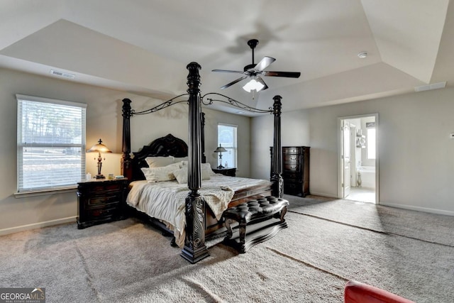 bedroom with ceiling fan, connected bathroom, a raised ceiling, and carpet floors