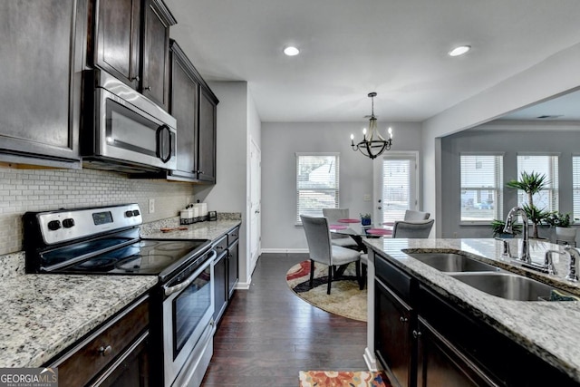 kitchen featuring pendant lighting, sink, stainless steel appliances, light stone counters, and dark brown cabinetry