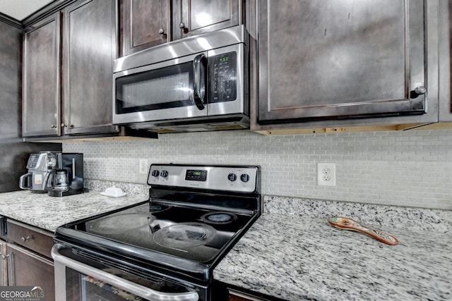 kitchen featuring stainless steel appliances, light stone countertops, dark brown cabinets, and backsplash