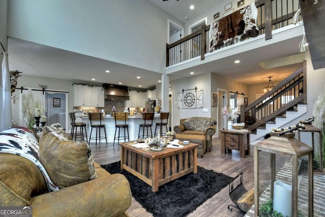 living room with hardwood / wood-style flooring, a barn door, and a high ceiling