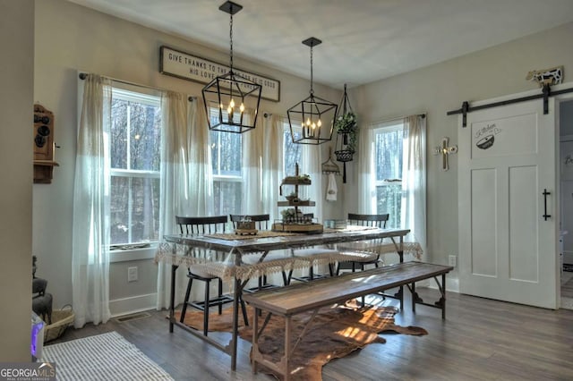 dining area with a barn door and hardwood / wood-style floors