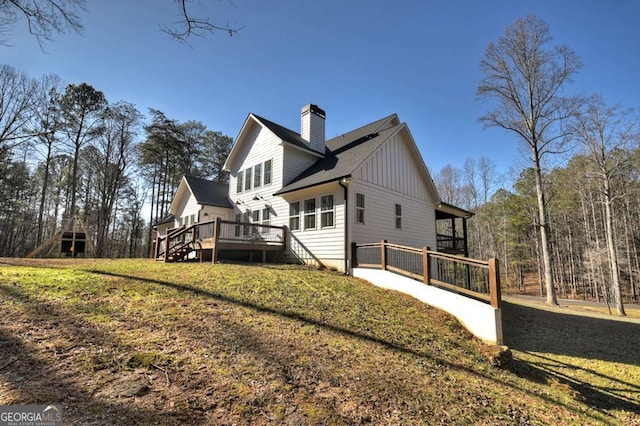 back of property featuring a wooden deck and a yard