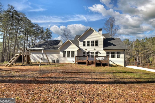 rear view of house with a wooden deck and a yard