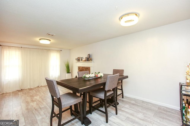 dining space with light hardwood / wood-style floors and a textured ceiling