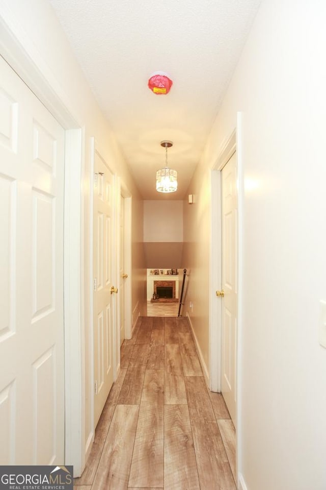 corridor featuring a chandelier and light hardwood / wood-style flooring