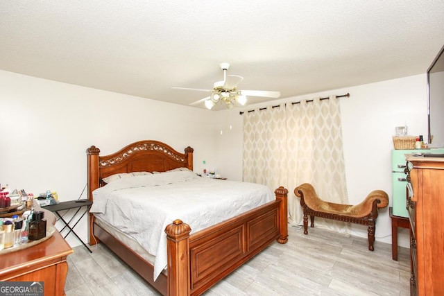 bedroom featuring ceiling fan, light hardwood / wood-style flooring, and a textured ceiling