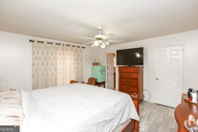 bedroom with ceiling fan, a textured ceiling, and light hardwood / wood-style floors