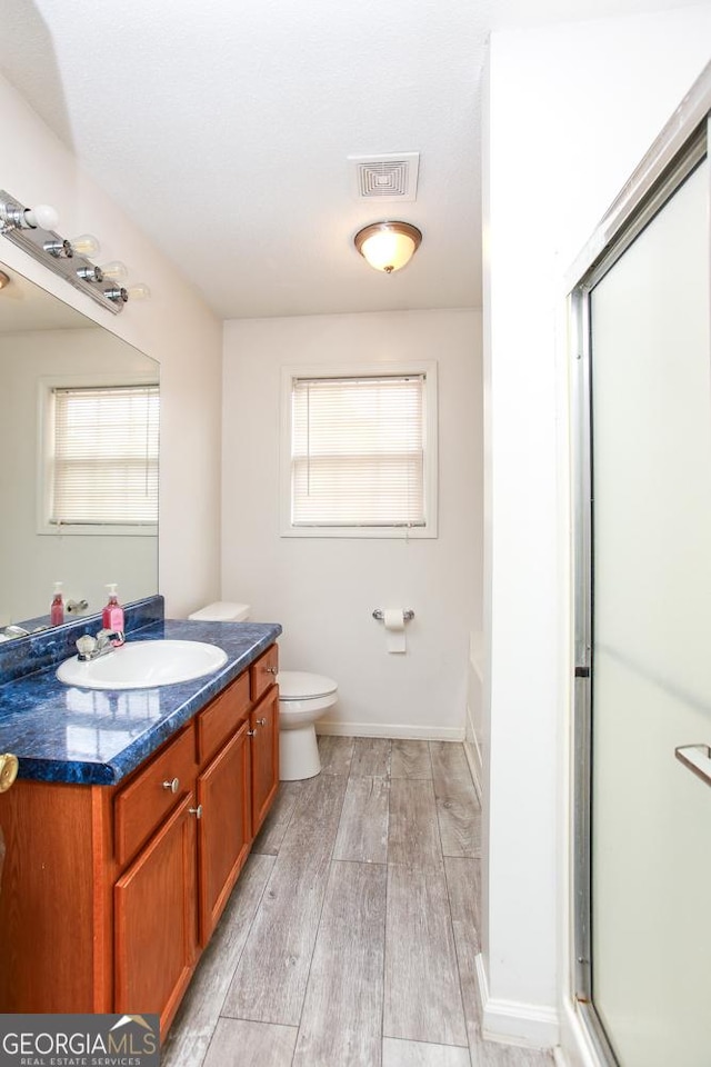 full bathroom with toilet, vanity, plus walk in shower, and hardwood / wood-style floors