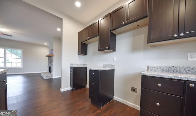 kitchen featuring dark hardwood / wood-style flooring, dark brown cabinets, and light stone countertops