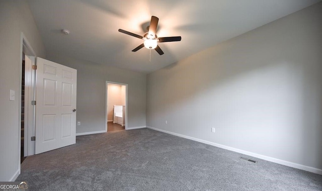 unfurnished bedroom with ceiling fan, ensuite bathroom, and dark carpet