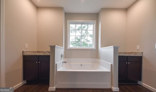 bathroom with vanity, a washtub, and wood-type flooring