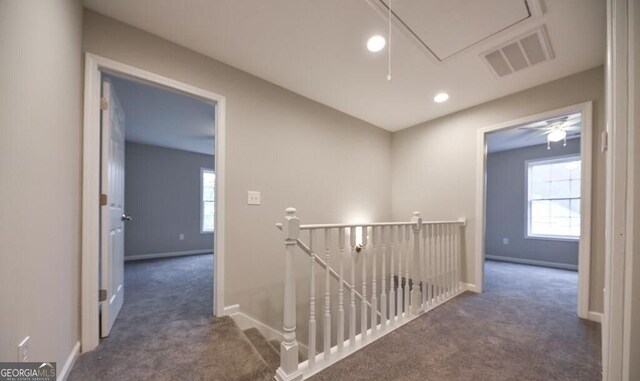 hall featuring dark colored carpet