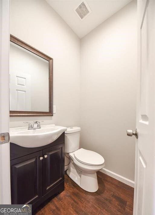 bathroom with vanity, hardwood / wood-style floors, lofted ceiling, and toilet