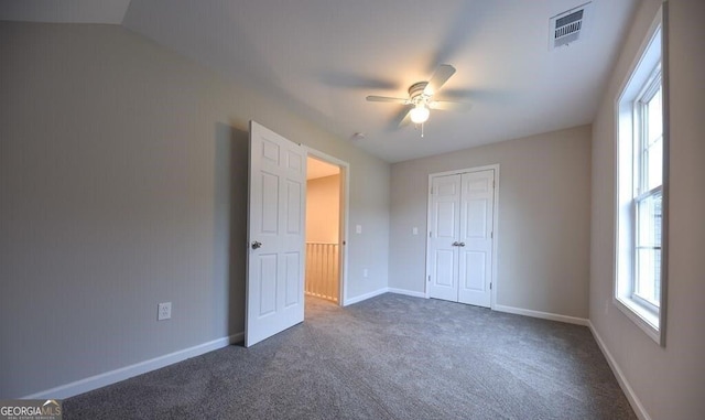 unfurnished bedroom with ceiling fan, dark carpet, and a closet