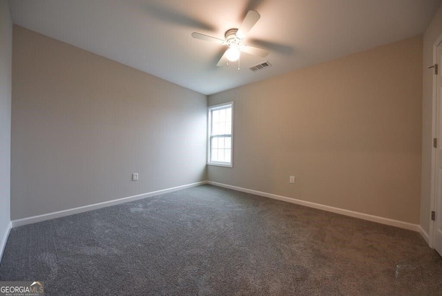 empty room with ceiling fan and dark carpet