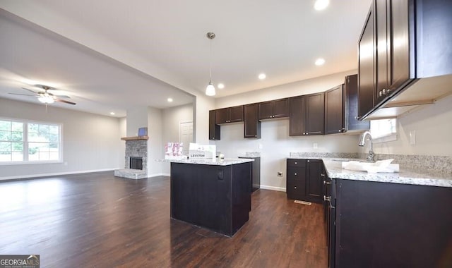 kitchen with dark hardwood / wood-style flooring, decorative light fixtures, a fireplace, and light stone countertops