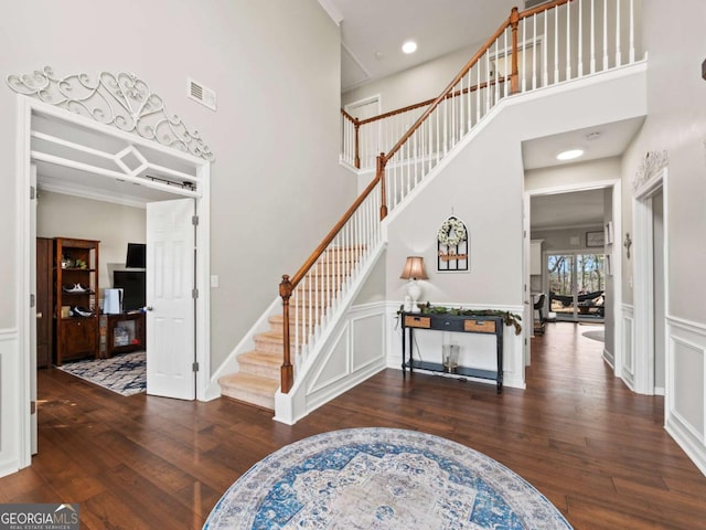 foyer entrance featuring ornamental molding, dark hardwood / wood-style floors, and a high ceiling