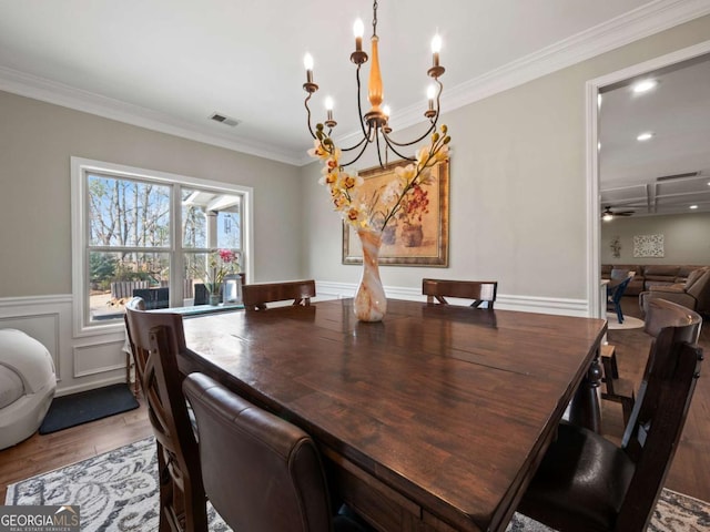 dining space with hardwood / wood-style flooring, ornamental molding, and ceiling fan with notable chandelier