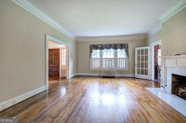 unfurnished living room featuring hardwood / wood-style flooring, a premium fireplace, and radiator heating unit