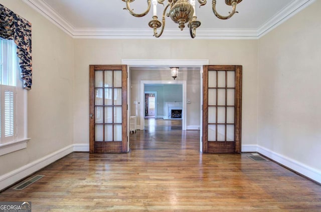 unfurnished dining area with an inviting chandelier, radiator heating unit, crown molding, and hardwood / wood-style floors