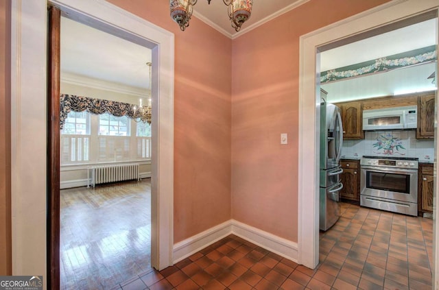 kitchen with radiator, decorative backsplash, stainless steel appliances, crown molding, and an inviting chandelier