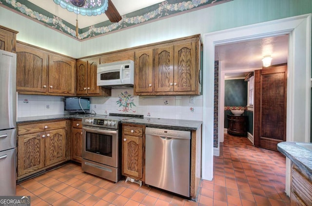 kitchen with tasteful backsplash, ceiling fan, appliances with stainless steel finishes, and dark stone counters