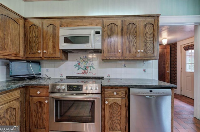 kitchen with backsplash, appliances with stainless steel finishes, and dark stone counters