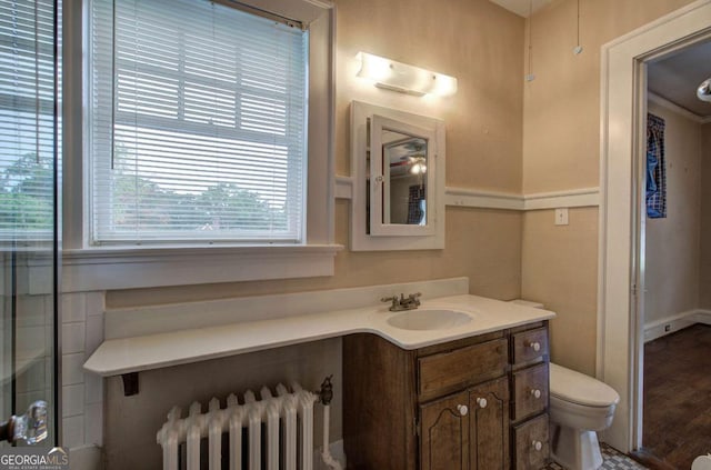 bathroom with vanity, radiator, hardwood / wood-style floors, and toilet