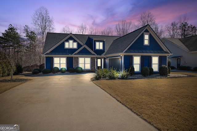 view of front of home with a garage, concrete driveway, stone siding, metal roof, and a standing seam roof