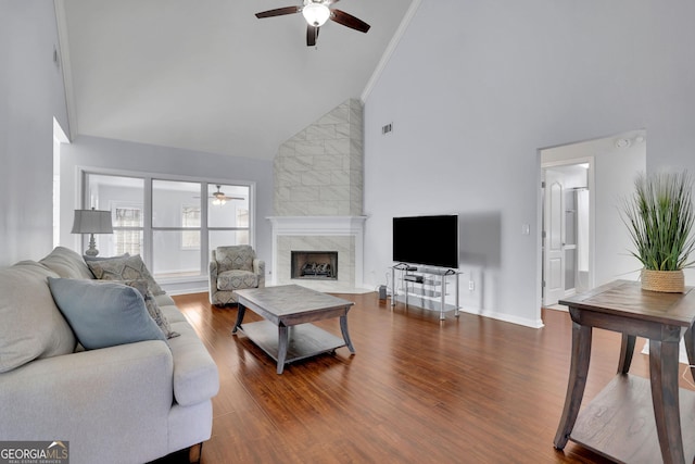 living room with a ceiling fan, a tiled fireplace, and wood finished floors