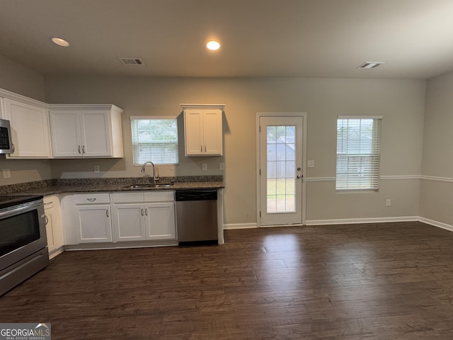 kitchen featuring sink, stainless steel appliances, dark hardwood / wood-style floors, white cabinets, and dark stone counters