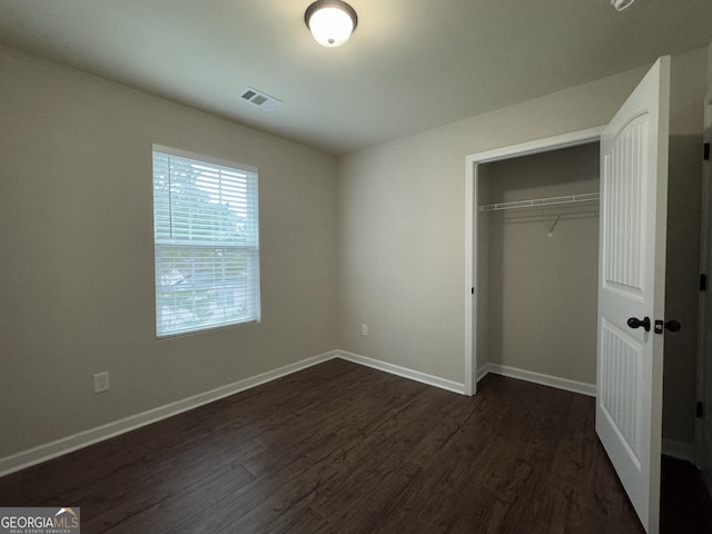 unfurnished bedroom with dark wood-type flooring and a closet