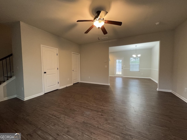 empty room featuring ceiling fan with notable chandelier and dark wood-type flooring