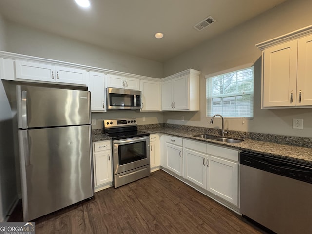 kitchen with white cabinetry, appliances with stainless steel finishes, sink, and dark stone countertops