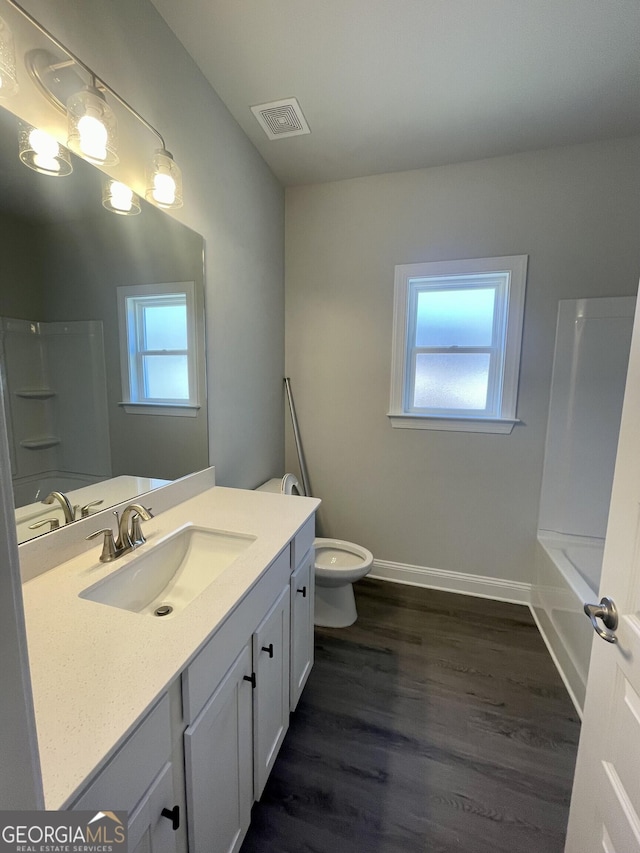 full bathroom with baseboards, visible vents, toilet, wood finished floors, and vanity