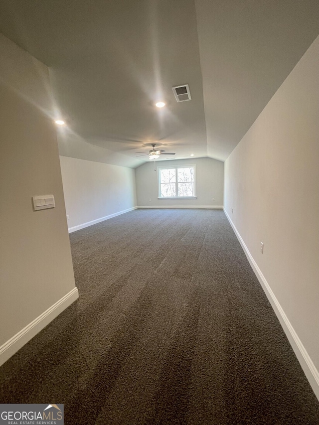 carpeted empty room with lofted ceiling, baseboards, visible vents, and ceiling fan