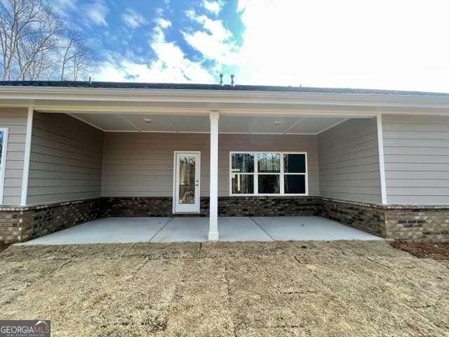 view of exterior entry with a yard, a patio area, and brick siding