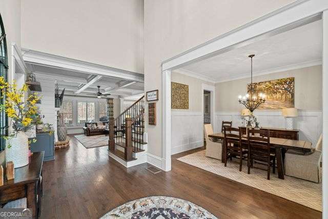 dining room with coffered ceiling, crown molding, hardwood / wood-style floors, beam ceiling, and ceiling fan with notable chandelier