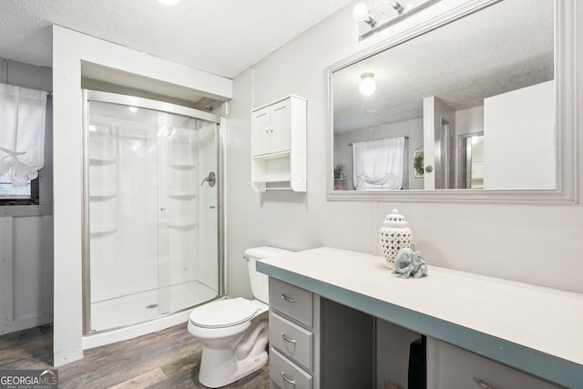 bathroom featuring hardwood / wood-style floors, vanity, walk in shower, toilet, and a textured ceiling