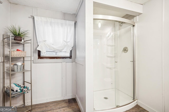 bathroom with a shower with door and hardwood / wood-style floors